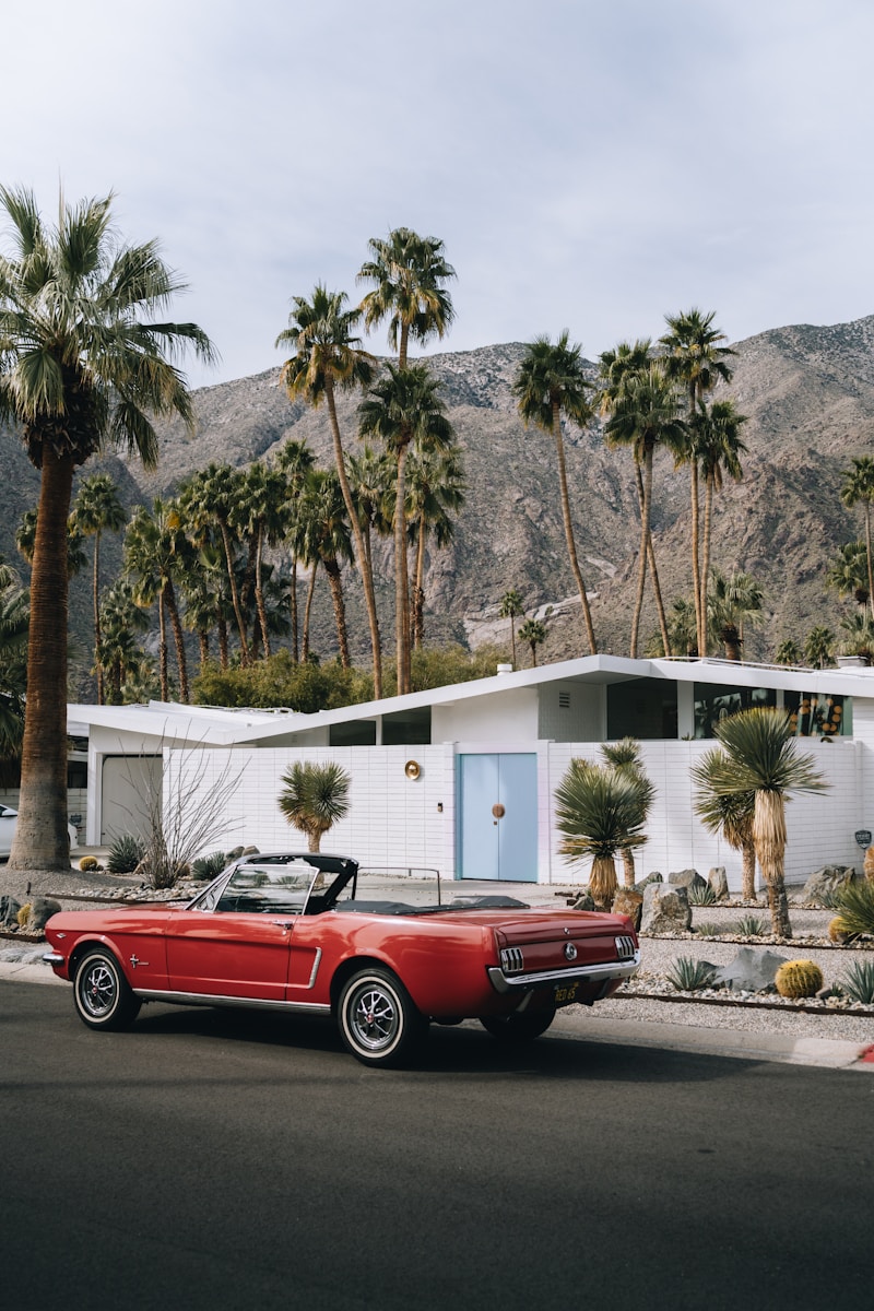 a red convertible car with auto insurance parked in front of a house